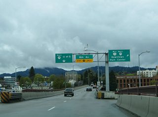 An extremely sharp turn is required for the 6th Avenue ramp from Coburg Road southbound. A set of overheads tout the connections to downtown and the Holt Center. The entertainment venue lies between 6th and 7th Avenues at Willamette Street, four blocks to the east.
