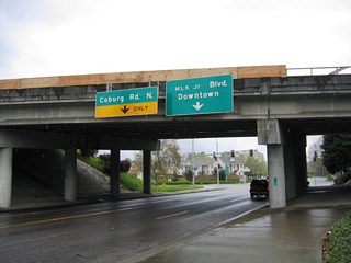 Country Club Road eastbound at the Interstate 105 & OR 126 overpass between Southwood Lane and Club Road. Motorists bound for Coburg Road and Interstate 105 east should turn left ahead onto the continuation of Country Club Road. Club Road begins ahead and travels east to Martin Luther King Jr. Boulevard near Autzen Stadium. The right side overhead is incorrect in that Club Road does not provide access to downtown via Coburg Road south.