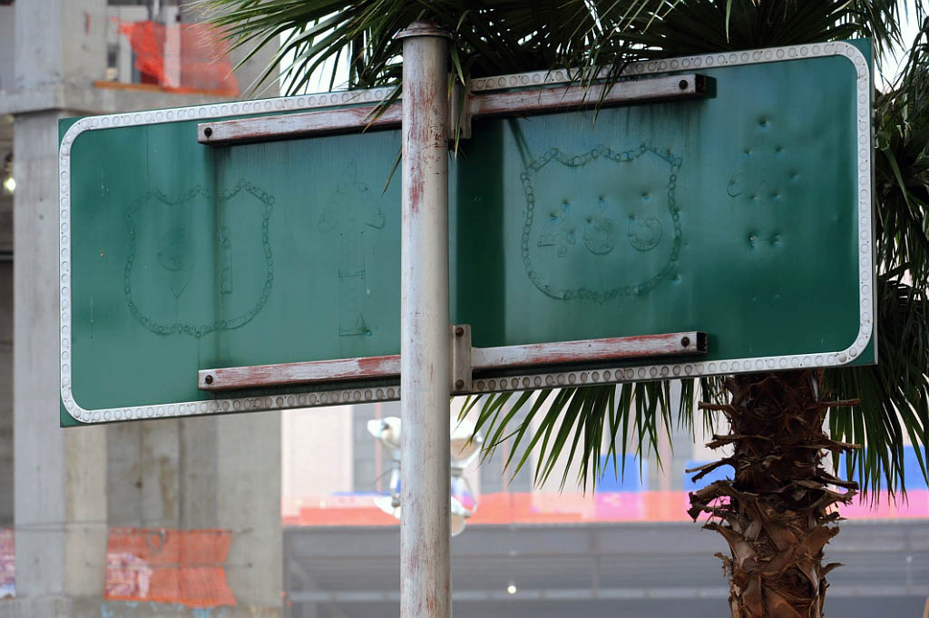 Late 1950s button copy guide sign on Las Vegas Boulevard (the Strip). Two outline shields for US-91 and US-466, and the corresponding arrows, are scraped off.