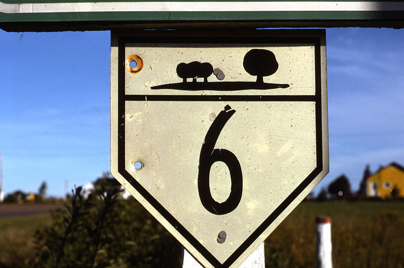 Oyster Bed Bridge. <br><br>
<i>I didn’t return to PEI until 1990. The numbering system had also been expanded and the signs much improved. But on an obscure 3-digit route, I found this remaining old marker as the route ended at PEI 6. Note that the tree pattern is different than the first. Were they hand-painted? I’m not sure, but these two designs sure are different.</i>