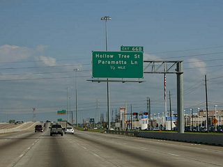 Exit 66B is a split diamond interchange joining IH 45 with Parrametta Lane east and Hollow Tree Lane west ahead of Cypress Creek.
