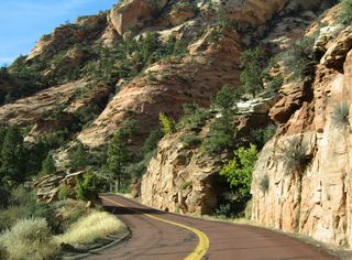 The Zion-Mount Carmel Highway (SR 9) advances west to Bridge Mountain, under which the highway will pass to reach the Zion Narrows.
