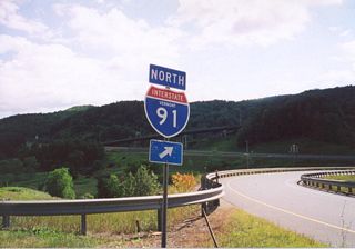Interstate 91 trailblazer at the northbound entrance ramp from U.S. 2 east. The nearby overpass takes VT 2B across I-91.