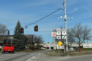 Two lanes turn onto U.S. 7 (Shelburne Road) south across from an entrance to Shelburne Road Plaza shopping center.