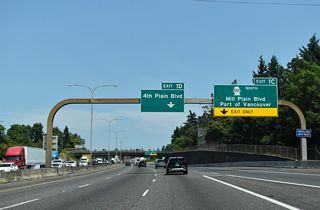Exits 1 C to Mill Plain Boulevard / Port of Vancouver and 1 D to 4th Plain Boulevard depart simultaneously within a quarter mile from this arched sign bridge. The arch theme of the sign bridges is echoed by the simple curved shapes of the double arm street lamps that line the median.