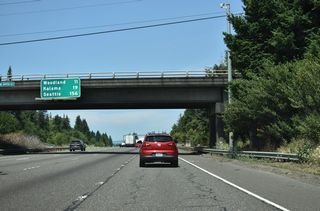 The distance sign for Woodland, Kalama, and Seattle is posted on the 199th Street overpass. A rest area next right sign was previously posted next to it.