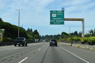 The dome of the Washington State Capitol appears above the tree line, a half mile ahead of Exit 104 for U.S. 101 north to Aberdeen and Port Angeles.