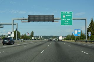 Continuing east across Fife, Interstate 5 spans Wapato Creek ahead of the six-ramp parclo interchange (Exit 137) with 54th Avenue E and the northbound beginning of SR 99.
