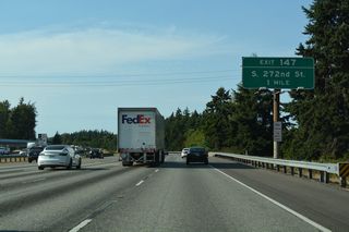 The diamond interchange at Exit 147 joins I-5 with S 272nd Street one mile north of the S 288th Street underpass. Suburban development lines both sides of the freeway to the Kent city line.
