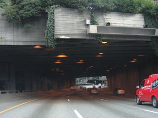 Interstate 5 north enters the Central Freeway Park tunnel. Seneca Street travels above the freeway beyond the northbound portal.