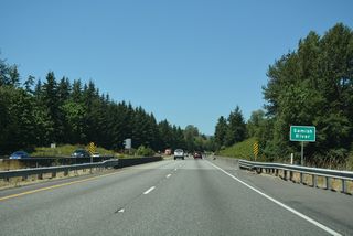 Beginning the ascent from Butler Flat, Interstate 5 crosses the Samish River ahead of a roadway separation at mile marker 295.