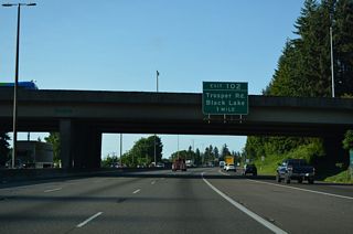 Exit 102 for Trosper Road to Black Lake, follows a mile south of the Custer Way overpass. Trosper Road briefly connected U.S. 99 from the 1950s expressway south of Exit 102 with adjacent Capitol Boulevard. Capitol Boulevard was U.S. 99 until 1958.