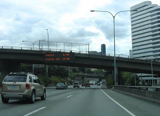 A dynamic message sign at the Denny Way overpass indicates travel times to cities south of Seattle.
