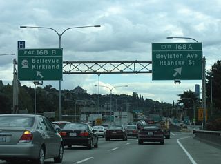 Exit 168 A departs Interstate 5 from the south end of the Lake Washington Ship Canal bridge to join parallel Boylston Avenue south ahead of Roanoke Street at the North Broadway community. Exit 168 B leaves simultaneously for SR 520 east to Kirkland, Bellevue and Redmond.