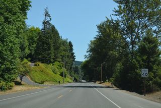 Business Loop I-5 (Huntington Avenue) passes Castle Rock (elevation 190 feet) ahead of Lions Pride Park along the adjacent Cowlitz River.