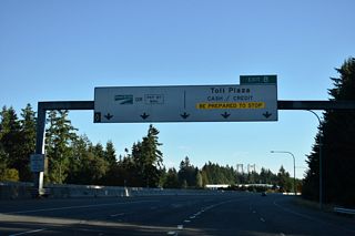 Towers of the Tacoma Narrows Bridge rise along the horizon ahead of the toll collection facility on SR 16. Three lanes are allocated for WSDOT Good to Go! account holders.