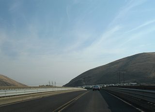 A 1941-built bridge retrofitted with metal guard rails spans a Washington Central Railroad beyond the ramp split to Interstate 82. Union Gap, the cut between Ahtanum Ridge and Rattlesnake Hills, lies in the background.