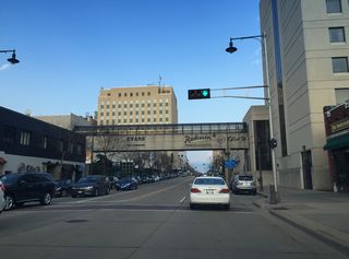 College Avenue approaches the skyway that connects a parking ramp to the Paper Valley Hotel. The hotel hosts visiting teams that play the Packers. The tall building to the left is the 222 building, the tallest building in Appleton.