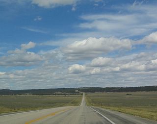 U.S. 14 is long and straight as it travels north, leaving the Powder River Basin and entering the Black Hills of Wyoming. The dense forest ahead helps to give the Black Hills its name when compared to the surrounding sagebrush prairie.
