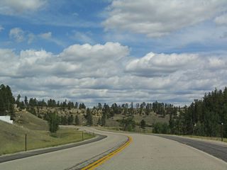 Sandstone cliffs appear in the distance as U.S. 14 rounds another bend within the Black Hills.