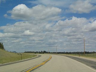 Devils Tower, which is the destination of many travelers on this stretch of U.S. 14 (since Interstate 90 is a more direct route between Moorcroft and Sundance), comes into view as the road passes over another summit. Look to the right in the photo to see the famous volcanic mountainous plateau; keep in mind that U.S. 14 is generally traveling north or northeast between Keyhole Reservoir and Carlile.