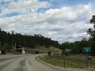 A small sign indicates that eastbound U.S. 14 has reached the community of Carlile. U.S. 14 shifts from northeast to east as it turns toward the Oshoto turnoff and Devils Tower Junction.