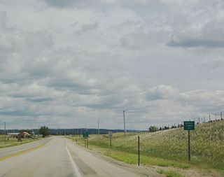 A small placard sign designates the junction of U.S. 14 and Wyoming 24 as Devils Tower Junction. Note the reduction of speed limit here as well as the limited services on the north side of the highway.