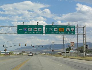 This overhead sign points the way for the split between U.S. 20-26 and Business U.S. 20-26. Follow U.S. 20-26 east to bypass Casper and connect directly to Interstate 25. Interstate 25 and U.S. 20-26-87 merge together, remaining north of downtown Casper as the freeway travels east toward the cities of Glenrock and Douglas. U.S. 20-26 east to the Casper Events Center, which is the location of concerts and theater events. Business U.S. 20-26, meanwhile, travels east along Yellowstone Highway into Mills, enters Casper, meets Wyoming 220 (Poplar Street), and crosses the North Platte River bridge. Following First Street, the business route enters downtown Casper. At the intersection with Center Street in Casper, Business U.S. 20-26 merges with Business Loop I-25 and Business U.S. 87; the four routes then turn northeast via Yellowstone Highway to return to Interstate 25 and U.S. 20-26-87 at Exit 186.