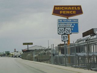 U.S. 20-26 Business-87 is signed as the business route passes by a fence supplier.