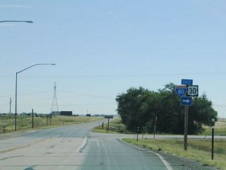 Eastbound U.S. 30 turns right onto the connector road. The third generation of Lincoln Highway follows the service road, while the original alignment of the Lincoln Highway veers away from Interstate 80, following the Union Pacific Railroad northeast toward Burns and Egbert before rejoining Interstate 80 and U.S. 30 at Pine Bluffs. While sections are paved, substantial sections of this original Lincoln Highway alignment are not paved.