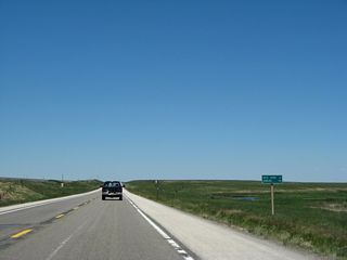 This mileage sign provides the distance to Rock River (21 miles) and Rawlins (96 miles); the brown sign identifies U.S. 30-287 as part of the Sand Creek Massacre Trail.