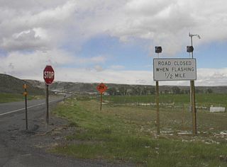 Like most Wyoming highways in rural areas, closures during inclement weather, such as winter snowstorms and windstorms, are posted by white regulation signs such as this one along WY-120 north at County Route 3KD.