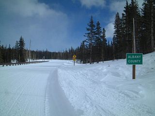 Eastbound Wyoming 130/Snowy Range Road reaches the Albany-Carbon County Line during the middle of winter. Wyoming 130 is only open to cross-country skiers and snow machines during the winter months, since it is too intrusive to plow the highway free of the several feet of snow on Wyoming 130 between October and May each year.