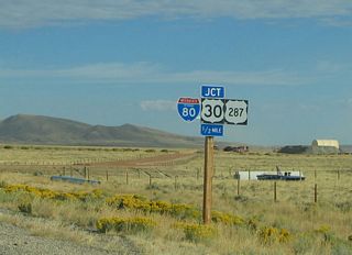 Northbound Wyoming 130-230 approach their junction with Interstate 80 and U.S. 30-287. The freeway ramps are just ahead; two-lane Wyoming 130 transitions directly onto U.S. 30-287 eastbound.