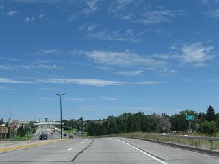 After the initial route marker assembly, Interstate 180 crosses over Deming Drive and Crow Creek. Frontage roads line Interstate 180 on either side of the expressway. Interstate 180 has standard shoulders and a low concrete median barrier.