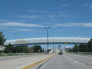 Interstate 180, Business Loop I-25, U.S. 85, and Business U.S. 87 pass under a pedestrian bridge.
