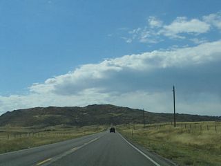 A large mountain lies immediately ahead on westbound Wyoming 210/Happy Jack Road.