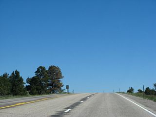 This series of pictures follows U.S. 287 north along the crest as we approach the summit of Pumpkin Vine Hill. Sight lines vary considably along this stretch, requiring motorists to use caution when passing in a blind area. Snow fences, designed to reduce wind speeds enough to cause blowing snow to drop behind a fence, become increasingly common as the viewshed gradually expands. Watch for sudden wind gusts on this often-windy stretch of remote highway.