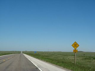 While these pictures show U.S. 287 as a two- lane highway, it has since been expanded to a four lane expressway complete with 76-foot wide median barrier. The highway will continue northwest toward Laramie. Now on the floow of the Laramie Basin, we see a semi-arid high plain with rolling hills and green grass, which was a function of a wet spring in 2008. Billboards for fireworks are common along this segment of U.S. 287, since the sale of fireworks is legal in Wyoming and restricted in Colorado. Toward the end of this set, U.S. 287 crosses over the Union Pacific Railroad tracks. This bridge has since been twinned to allow for the new expressway to pass over the railroad.