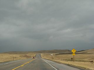 Southbound U.S. 287 begins its ascent up Pumpkin Vine Hill. Snow fences line the sides of the road to reduce snow blowing across the highway. Ominous thunderstorm clouds cover the horizon as the highway used to lose its climbing lane at the top of the hill.