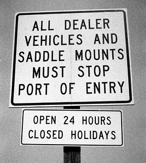 Regulatory signs posted along WY-585 north ahead of the Port of Entry near Sundance. The main sign in this assembly indicates that even vehicles which are legally regarded as merchandise in transit must stop at the port of entry in Sundance.