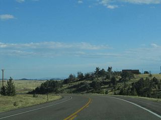 Lincoln Highway (Old U.S. 30) begins to descend from Sherman Hill. A single house rests on the hill in the distance.